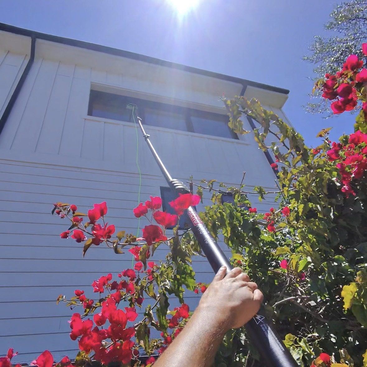 Elite technician using an extension pole to clean second-story windows