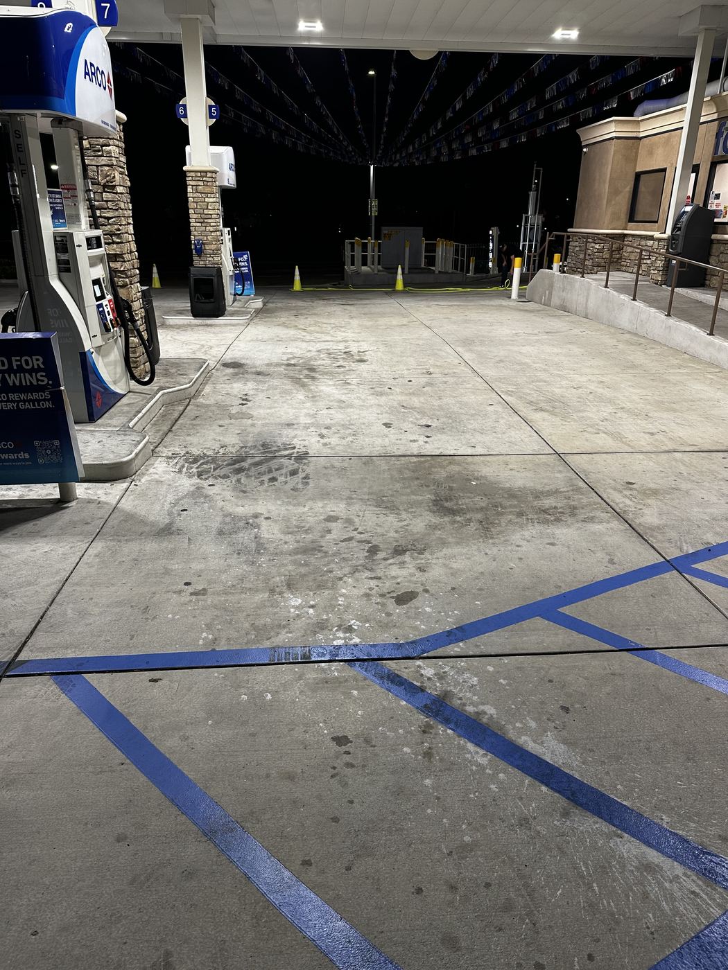 Before: stained, dirty concrete fuel island at a gas station at night