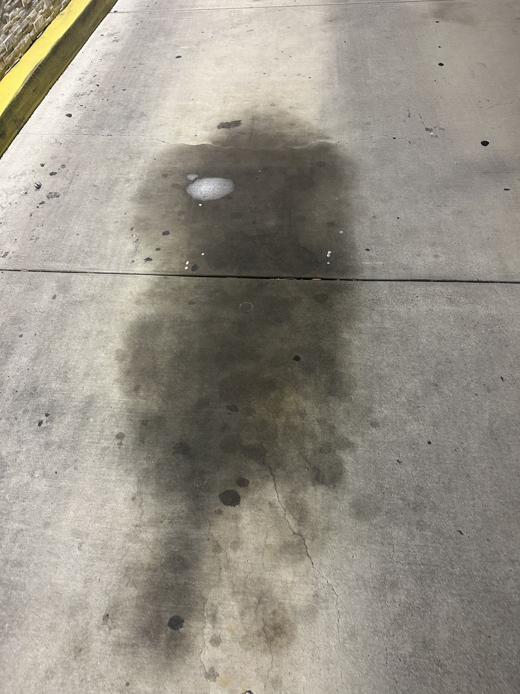 Heavy grease and oil staining on concrete near a restaurant's back service area