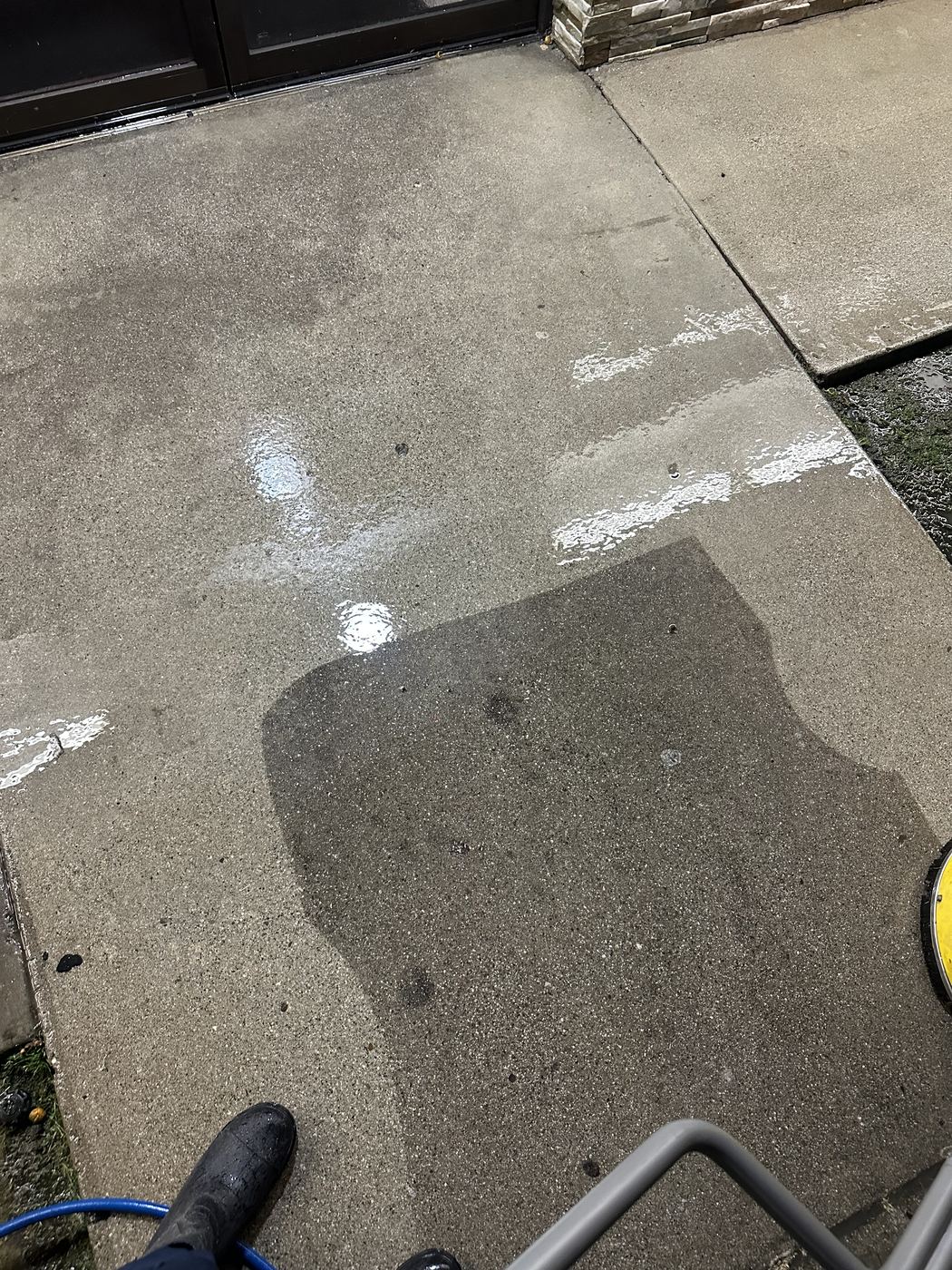 Restaurant back entrance concrete mid-cleaning, grease stains lifting
