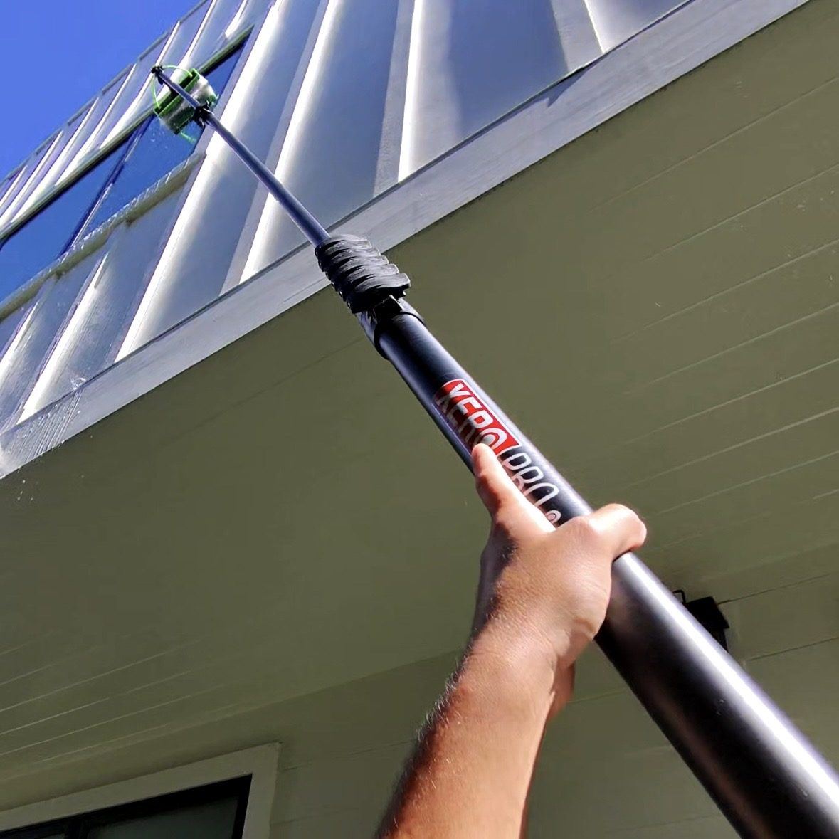 Window cleaning tool reaching a high window on a two-story home