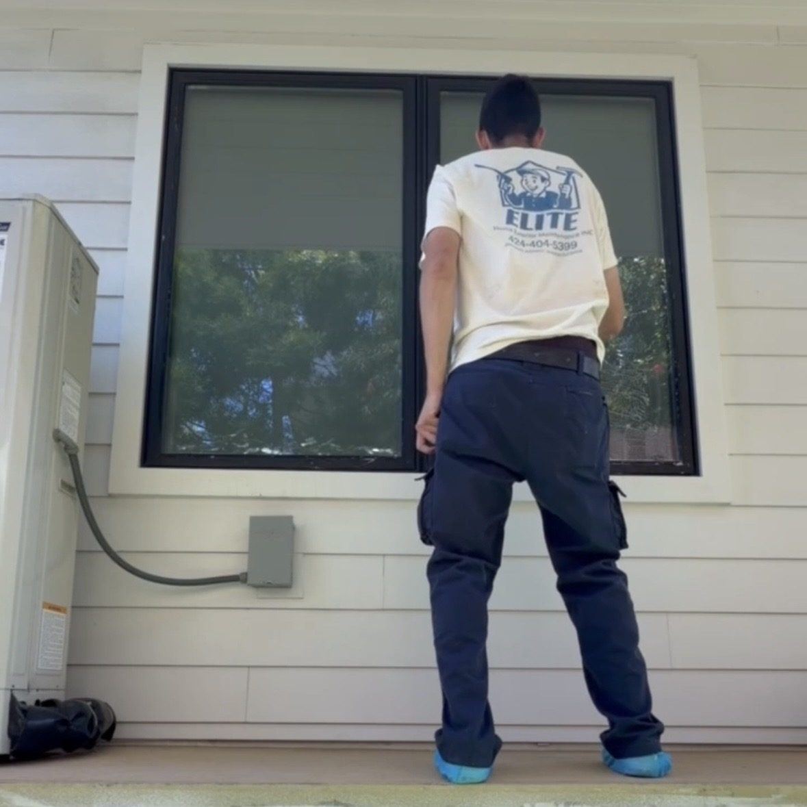 Elite Home Exterior Maintenance technician cleaning a window on site