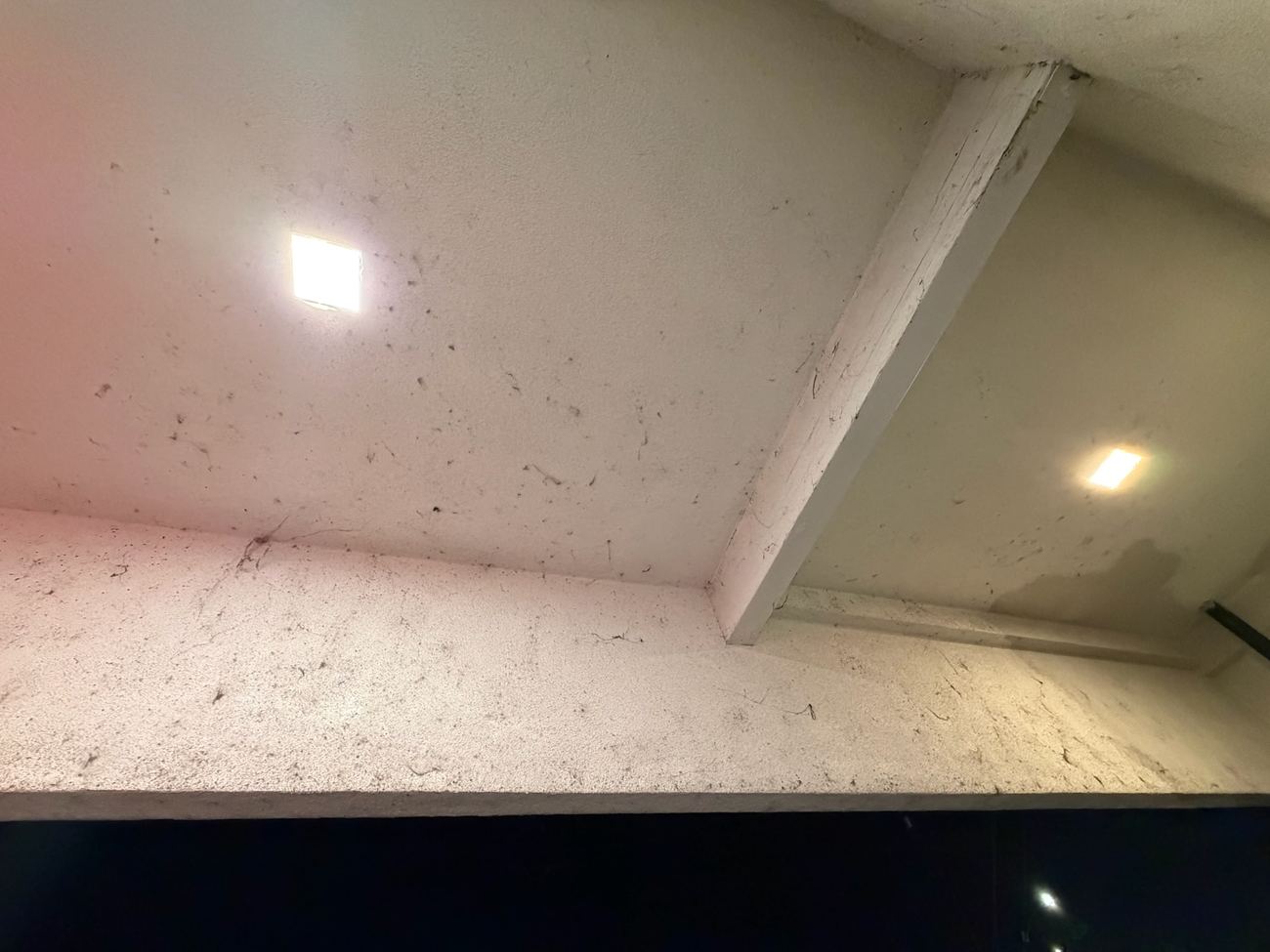 Before: heavy dust buildup on a commercial soffit near a light fixture