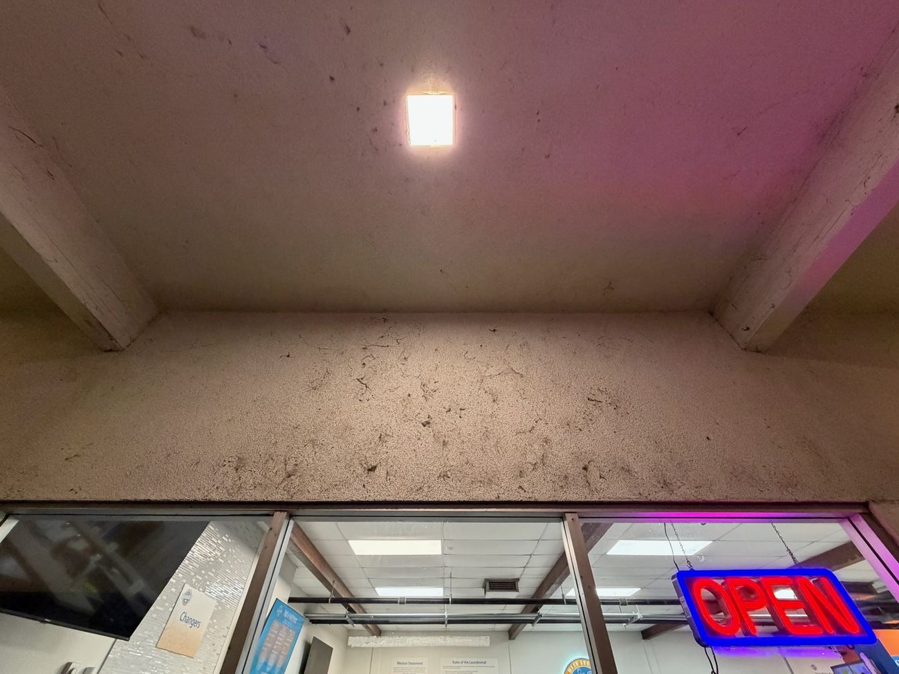 Before: dust and cobweb buildup on a commercial laundromat entrance overhang
